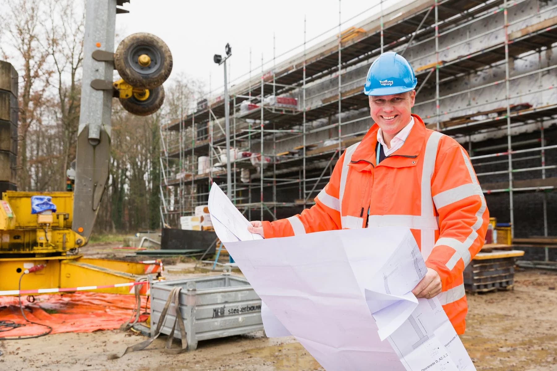 Vitens-medewerker met een bouwtekening op een projectlocatie